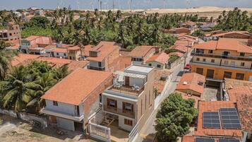Uma área residencial com telhados vermelhos, uma combinação de edifícios térreos e com vários andares, e algumas turbinas eólicas à distância.