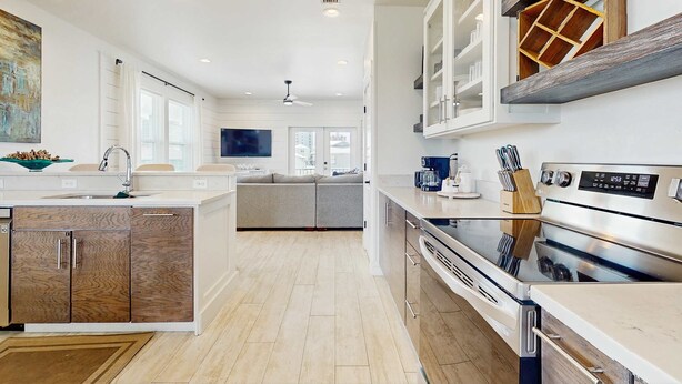 A modern kitchen with a central island, built-in cabinets, a stainless steel oven, and a ceiling fan. - New dog-friendly home with a private pool near the Gulf (Gulf Shores)