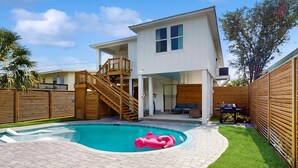 A modern two-story house with a swimming pool, wooden deck, and a staircase leading to the upper level. - New dog-friendly home with a private pool near the Gulf (Gulf Shores)