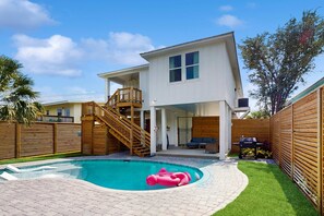 Ein modernes, zweistöckiges Haus mit Swimmingpool, Holzterrasse und einer Treppe, die zum Obergeschoss führt.