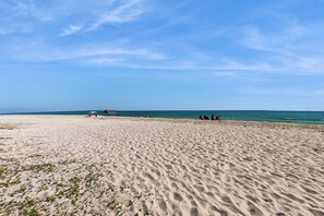 A beach with a thatched-roof structure, sandy terrain, and a clear sky. - Two-story home with WiFi, partial ocean views, covered deck, dock, and W&D (Fort Morgan)