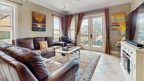 Ein Wohnzimmer mit Ledersofas, einem Couchtisch, einem Deckenventilator und Kunstwerken an den Wänden.