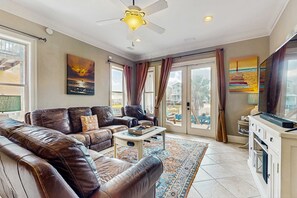 Ein Wohnzimmer mit Ledersofas, einem Couchtisch, einem Deckenventilator und Kunstwerken an den Wänden.