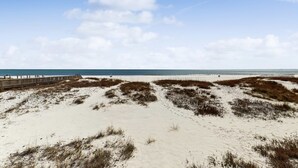 Une plage de sable avec une promenade en bois qui mène à l’eau.