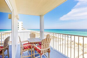 Ein Balkon mit Blick auf den Strand, ein Tisch und zwei Stühle.