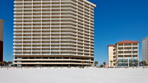 Ein Hochhaus-Hotel mit mehreren Balkonen, einer flachen Dachterrasse und direkter Strandlage.