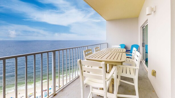 Ein Balkon mit Tisch und Stühlen, der Blick auf einen Strand und das Meer bietet.