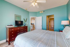 A bedroom with a bed, dresser, television, and a ceiling fan. - Gulf-front condo w 2 pools, sauna, hot tubs, fitness center & stunning views (Gulf Shores)