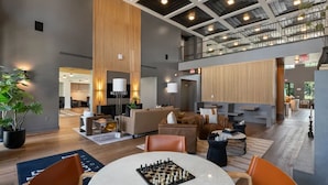 Eine großzügige Hotelhalle mit hoher Decke, einer zentralen Sitzecke mit Sofas und Sesseln, einem Tisch für Schachspiele und einem sichtbaren Westmont-Schild.