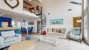A spacious living area with a staircase, a dining area, and a kitchen. - Centrally-located Gulf front paradise wfurnished sun deck & gorgeous water view (Gulf Shores)