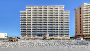 Ein Hochhotel mit mehreren Balkonen, Blick auf den Strand und einem modernen architektonischen Design.