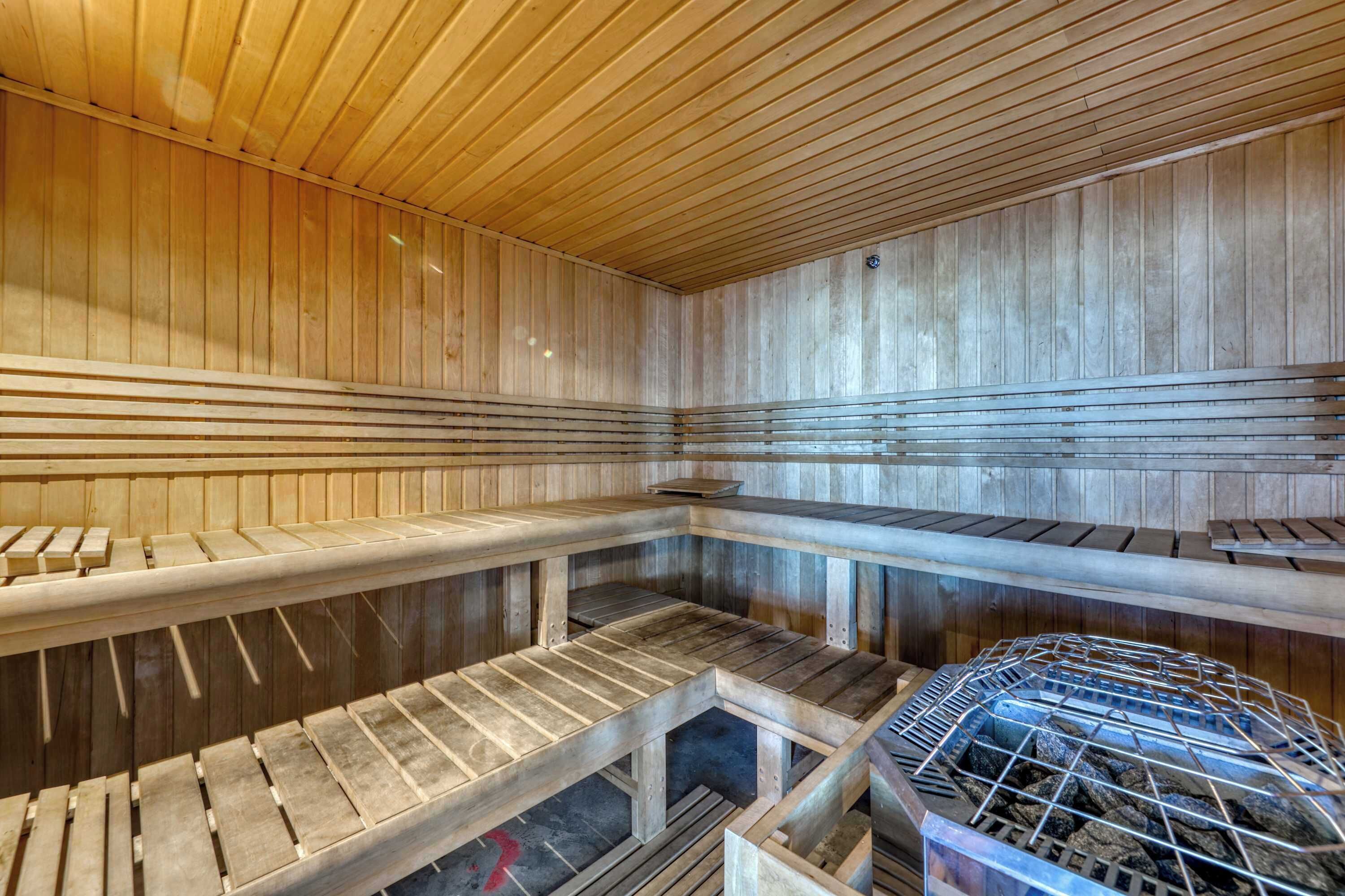 A sauna with wooden benches, a metal grid structure, and a wooden ceiling.
