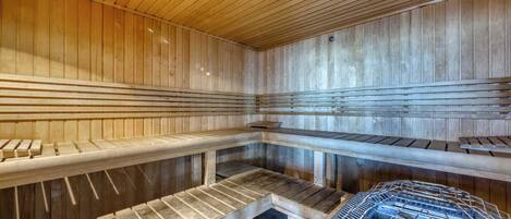 A sauna with wooden benches, a metal grid structure, and a wooden ceiling.