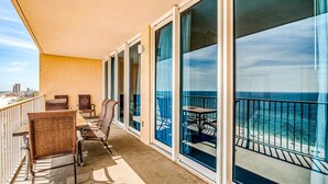 Ein Balkon mit Blick auf das Meer, Korbstühle und ein Tisch.