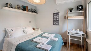 A neatly arranged bedroom with a bed, bedside tables, a desk, and shelves with various items. - Annex Bedroom – Oporto Garden (Porto)