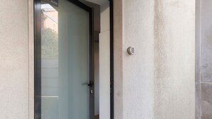 A door with a frosted glass panel and a keyhole, a textured wall, and a small plant. - Annex Bedroom – Oporto Garden (Porto)