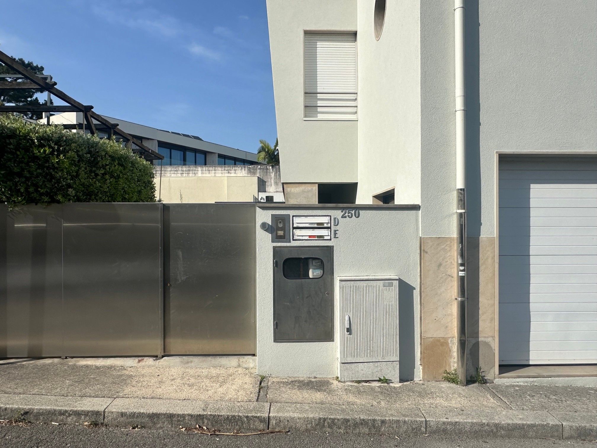 A building with a metal gate, a small utility box, and a garage door.