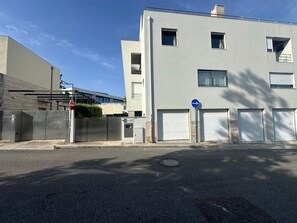 Un edificio con entrada protegida por un portón, un letrero de prohibido el acceso y una señal de flecha direccional.