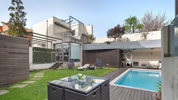 A modern outdoor patio with a glass-top table, a pool, and a wooden deck. - Annex Bedroom – Oporto Garden (Porto)