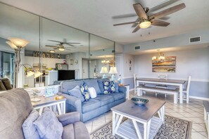 A living room with a sofa, coffee table, and dining area with benches. - Spacious and inviting seaside condo with shared pools, sauna (Fort Morgan)