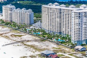 Ein Hochhaus-Hotel mit mehreren Balkonen, einem Zugangsweg zum Strand und einem Poolbereich.