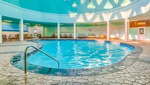 Piscina interior com teto transparente e chão revestido de azulejos.