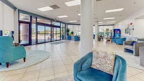 Um hall amplo com um sofá azul, uma poltrona verde-água e uma almofada estampada.