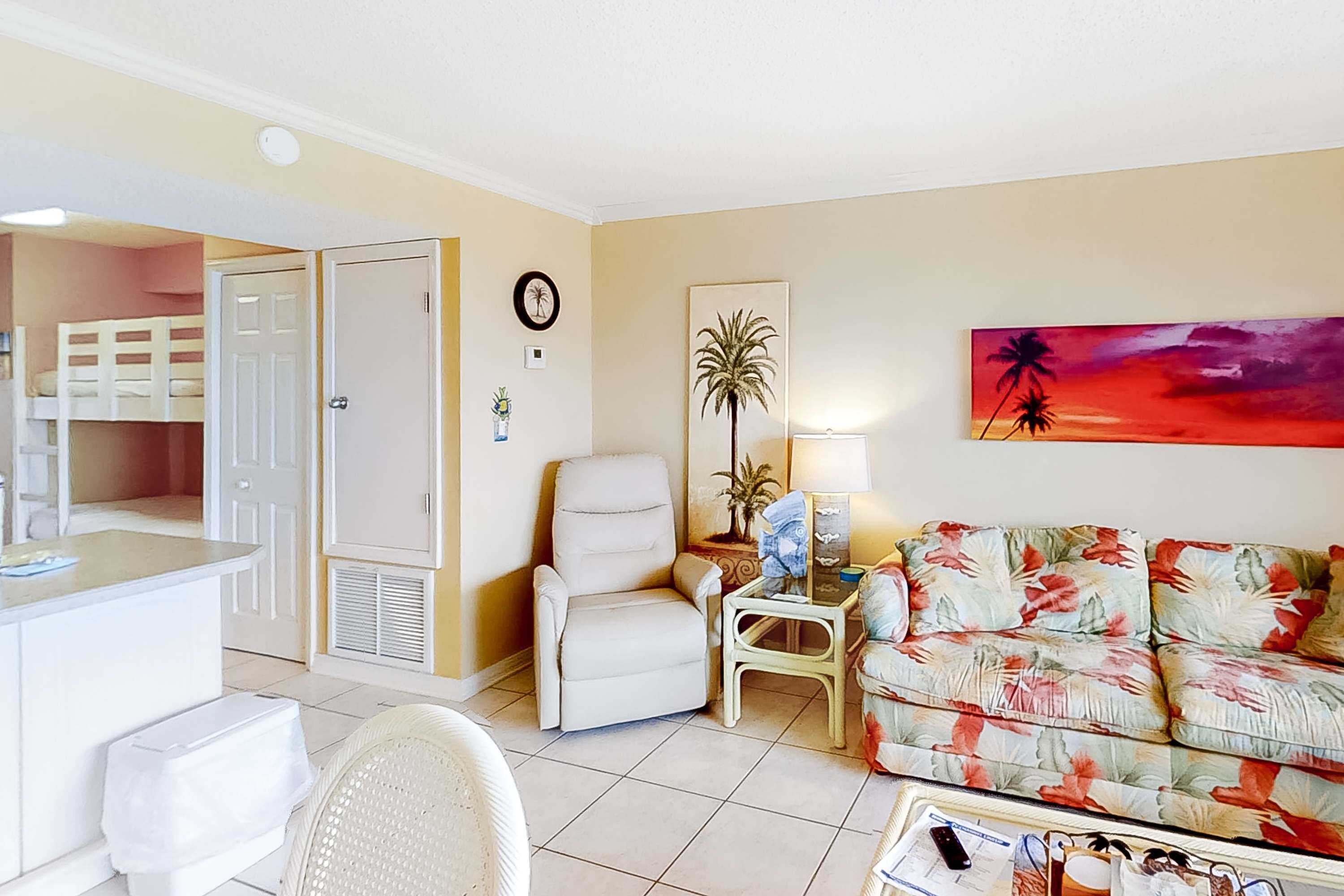 A living room with a sofa, a chair, a small table, a lamp, and a painting on the wall.