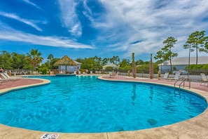A swimming pool with lounge chairs and a thatched-roof structure. - Gorgeous cottage with great amenties (Fort Morgan)