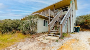 A house with a wooden staircase leading to a porch. - Beachfront home with furnished deck, great location, & WiFi (Fort Morgan)