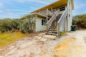 A house with a wooden staircase leading to a porch. - Beachfront home with furnished deck, great location, & WiFi (Fort Morgan)