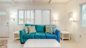 A living room with a teal sofa, white coffee table, and two side tables. - Beachfront home with furnished deck, great location, & WiFi (Fort Morgan)