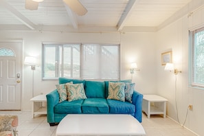 A living room with a teal sofa, white coffee table, and two side tables. - Beachfront home with furnished deck, great location, & WiFi (Fort Morgan)