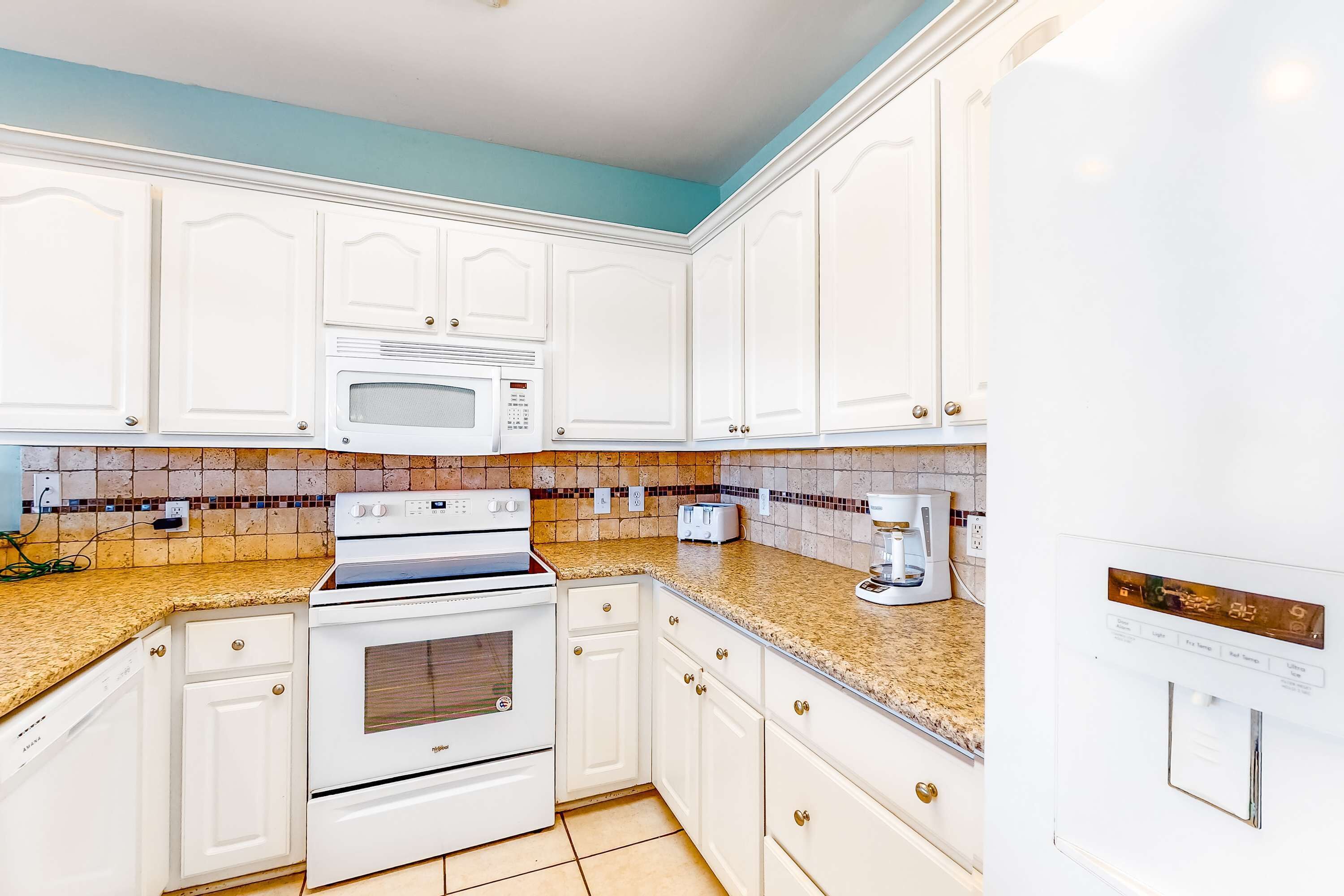 A kitchen with white cabinets, a microwave, a stove, and a coffee maker.