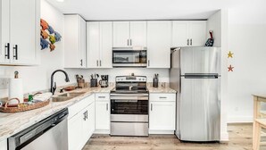 Una cocina moderna con armarios blancos, electrodomésticos de acero inoxidable y piso de madera.