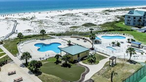 Et resort med flere swimmingpools, en strand og en bygning med grønt tag.