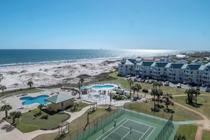 Un resort con playa, piscina, canchas de tenis y un edificio de techo verde.