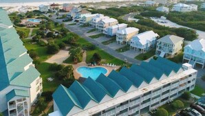 A coastal hotel with multiple-story buildings, a swimming pool, and a beach view. - Gulf view home with two-level deck, beach access & shared pools, hot tub, gym (Fort Morgan)