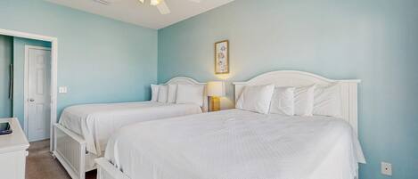 A bedroom with two beds, a ceiling fan, a door, and a nightstand.