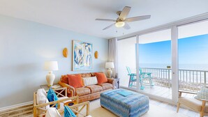 A spacious living room with a large window, a ceiling fan, and a view of the ocean. - Gulffront Condo W Furnished Deck, Beach Access, Fast WiFi & Shared Pool Hot Tub (Fort Morgan)