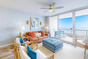 A spacious living room with a large window, a ceiling fan, and a view of the ocean. - Gulffront Condo W Furnished Deck, Beach Access, Fast WiFi & Shared Pool Hot Tub (Fort Morgan)
