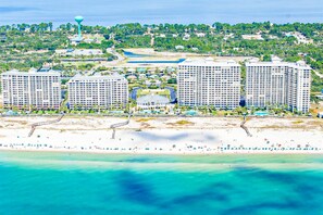 A coastal hotel with multiple high-rise buildings, a beach, and a water tower. - Gulffront Condo W Furnished Deck, Beach Access, Fast WiFi & Shared Pool Hot Tub (Fort Morgan)