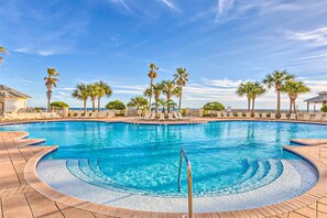 A swimming pool with a curved edge, palm trees, and a clear blue sky. - Gulffront Condo W Furnished Deck, Beach Access, Fast WiFi & Shared Pool Hot Tub (Fort Morgan)