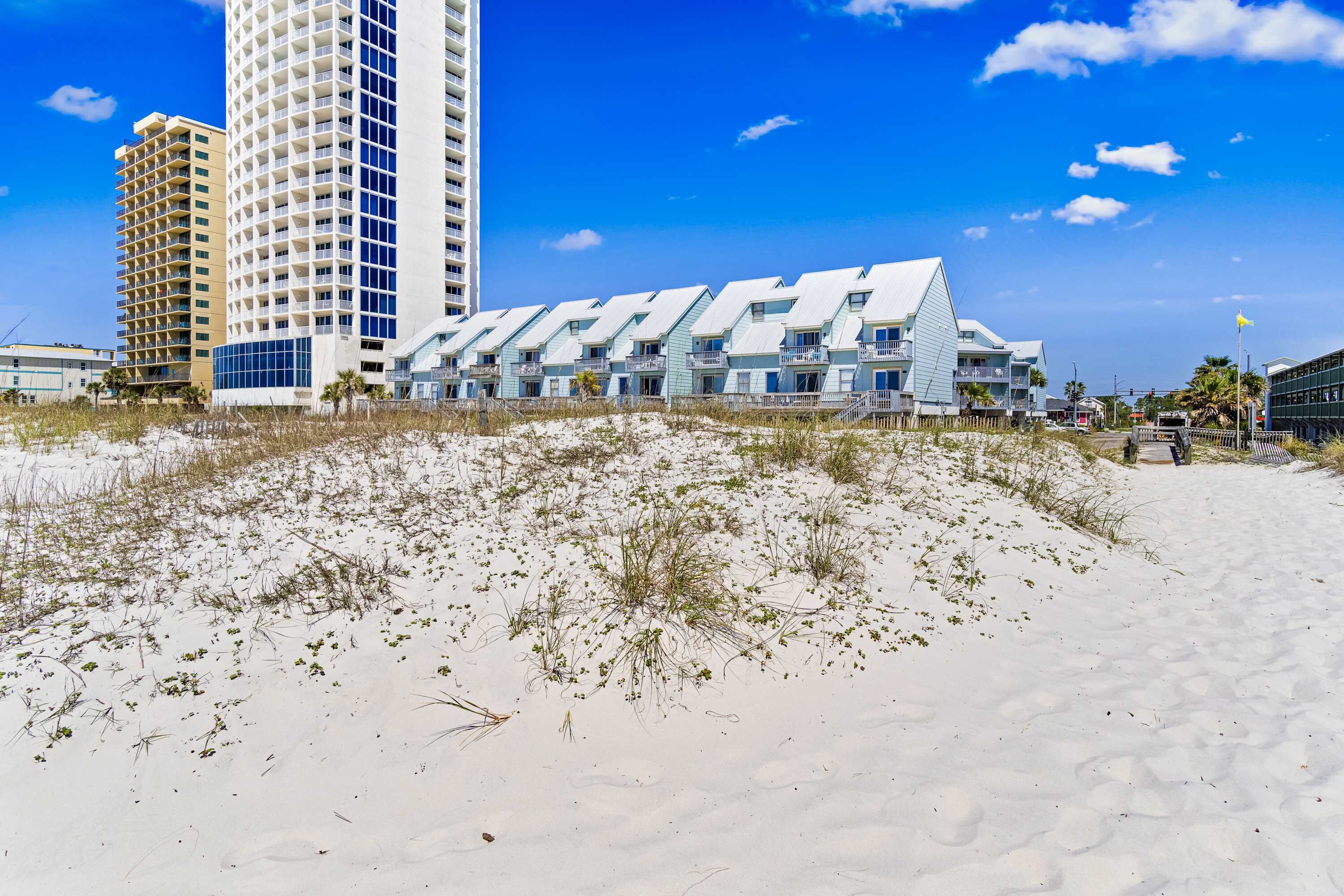 Ein Hotel direkt am Strand mit modernem Design, das ein markantes weißes Gebäude mit zahlreichen Balkonen und einer flachen Dachfläche zeigt.