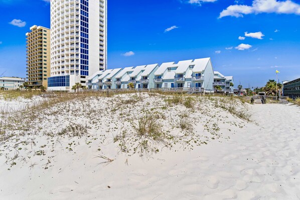 Ein Hotel direkt am Strand mit modernem Design, das ein markantes weißes Gebäude mit zahlreichen Balkonen und einer flachen Dachfläche zeigt.