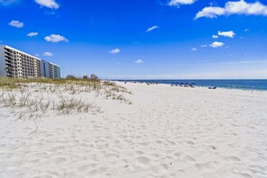 Ein Strand mit einem Hotel im Hintergrund.