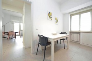 A dining area with a white table, two chairs, and a bowl. There are two wall-mounted artworks. - Welcome in Vatican vista apartment with Balcony (Roma)