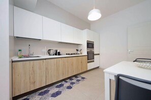 A compact kitchen with white cabinets, a microwave, and a sink. - Welcome in Vatican vista apartment with Balcony (Roma)