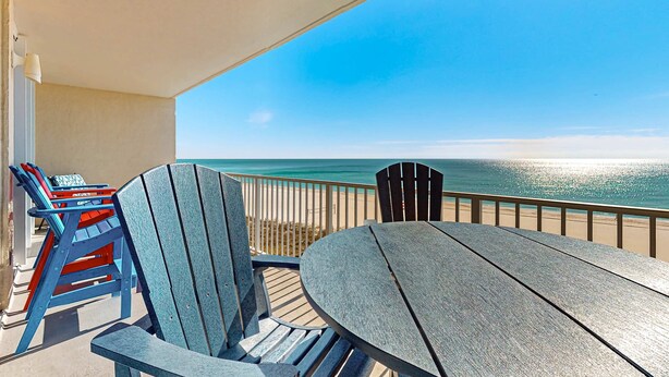 En balkon med udsigt over havet, et bord og stole.