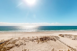A beach with a clear sky, sandy terrain, and a fence. - Colorful beachfront condo with Gulf views, pool, sauna, gym & W/D (Gulf Shores)